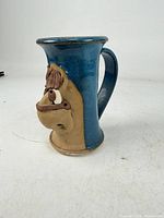 Front view of blue glazed mug with sculpted tan horse face