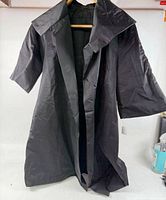 Front view of black vintage long coat on hanger showing wide collar and sleeve length