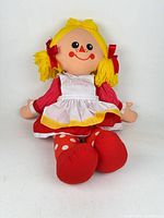 Front view of Daisy plush doll showing face, hair, apron detail