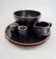 All six Dansk Mesa Black pieces stacked: two plates at base, bowl, creamer, two shakers on top.