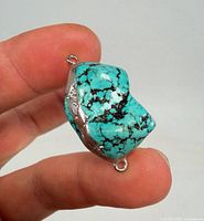 Front view of turquoise nugget with silver-tone mount and both loops visible