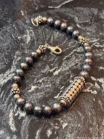 full view of bracelet showing pearls, silver spacers, cylindrical focal bead, lobster clasp