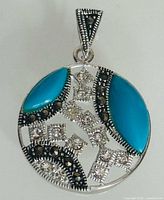 Front view of sterling silver pendant showing turquoise cabochons, marcasite and clear stones