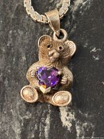 Front view of sterling silver teddy bear pendant with heart-shaped amethyst on box chain