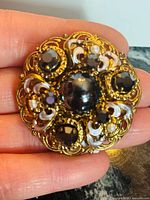 Front view of gold filigree brooch with black stones and pearls
