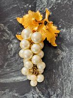 Front view of brooch showing faux pearl grape cluster and gold-tone leaves