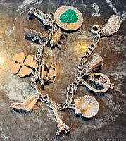 Full view of bracelet on dark surface showing link chain and assorted charms