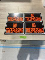 All four metal signs laid flat showing front graphics