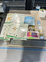 Overall lot on tabletop showing stencil packs, paint sets, palette and paint-by-number kit