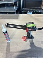 Cordless caulk gun and DAP caulk tube on table