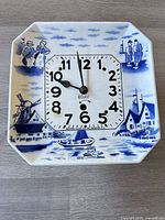 Front view showing Delft ceramic plate, painted scene and clock dial