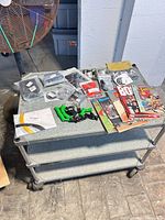 Overall view of all magazines, flags and sealed automotive accessories on metal cart