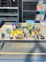 Full lot on table showing mix of garden tools, fertilizers, insect control, solar lights