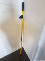 Full view of broom handle leaning against wall