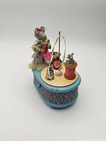 Oblique view showing mice figurines, thread spools, basket on blue floral base