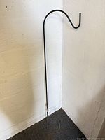 Full view of 48-inch black shepherd’s hook leaning against wall