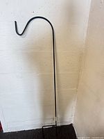 Full view of 48" black shepherd’s hook leaning against wall