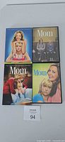 Front view of the four Mom DVD season box sets