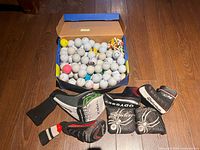 Box filled with mixed golf balls, tees and view of headcovers spread in front