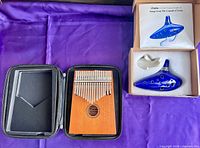 Kalimba in open zip case next to boxed ocarina, stand and songbook