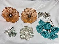 All items laid out: pair peach curtain tiebacks, six turquoise rose knobs, assorted clear faceted knobs