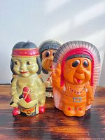 Three Indigenous character plastic coin banks grouped