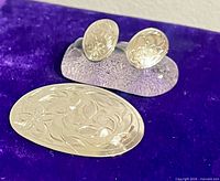 Brooch front and earrings on display showing design