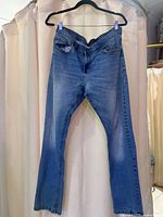 Pair of medium blue straight-leg jeans hung on hanger