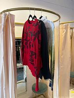 All three sweaters hanging: red with sequins, dark navy, gradient cable-knit