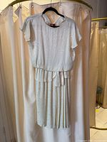 Ivory jacquard belted dress hanging on hanger