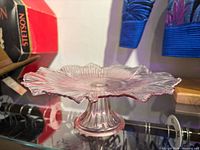 Angled front view of pink iridescent glass cake stand on display shelf