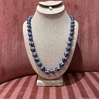 Full view of porcelain bead necklace on display bust