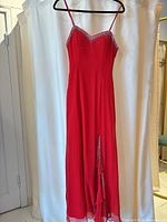 Full view of red silk evening dress on hanger