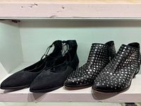 Both pairs of shoes on shelf – flats left, studded boots right