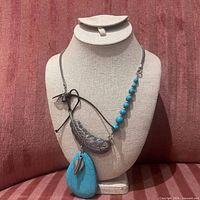 Turquoise pendant necklace with feather and beads displayed on bust