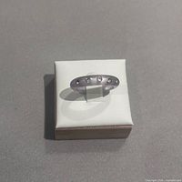 Ring with three flush clear stones displayed on small box
