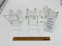 Group of clear acrylic adjustable display stands next to 12 in. ruler, hand-written note detailing quantities