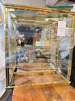 Full view of brass-tone framed glass display case with shelves and doors