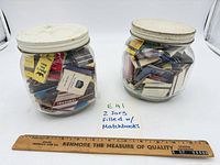 Two jars filled with matchbooks with ruler for scale