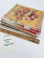 Stack of nine Woman's Day magazines with floral bouquet issue on top and ruler for scale