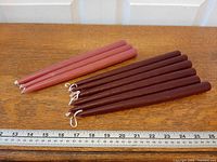 Group of nine taper candles beside ruler showing length