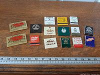 All fifteen matchbooks laid out on tabletop with ruler for scale