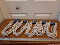 Five packaged ropes aligned on table with ruler for scale