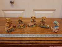 Five teddy bear figurines aligned with ruler for scale