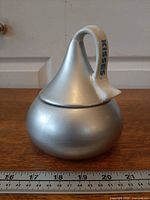 Full side view of silver ceramic Hershey's Kiss candy dish with lid showing matte finish and handle