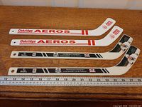 Four mini hockey sticks laid flat with ruler for scale