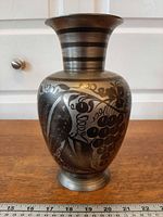Full front view of brass vase showing etched grape and leaf design, bulbous body, flared neck
