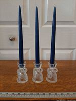Front view of three crystal swan candle holders with blue tapers