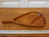 Full view of wooden leaf tray showing handle, two compartments, ruler for scale