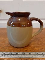 Front view of three-tone stoneware pitcher with ruler for scale